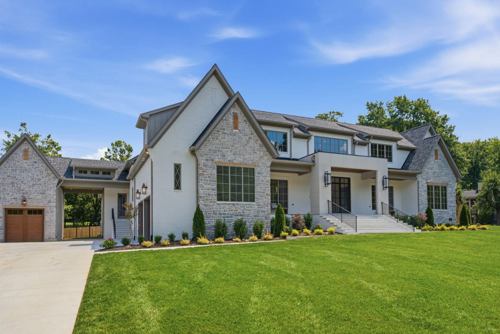 Stone and white brick custom home with gas lanterns and a deep summer lawn — designed by Mark Lynn Design, built by Broadway Builders, Nashville