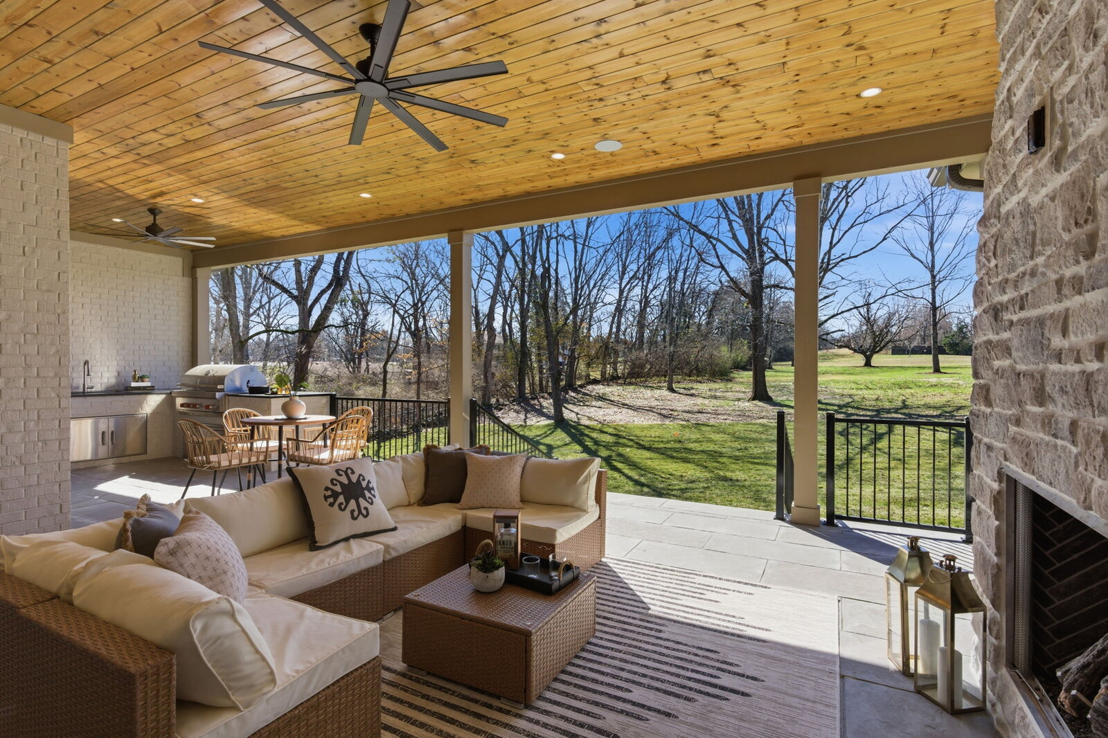 Covered outdoor living area with wood ceiling and stone fireplace on a Mark Lynn Design transitional farmhouse, Middle Tennessee