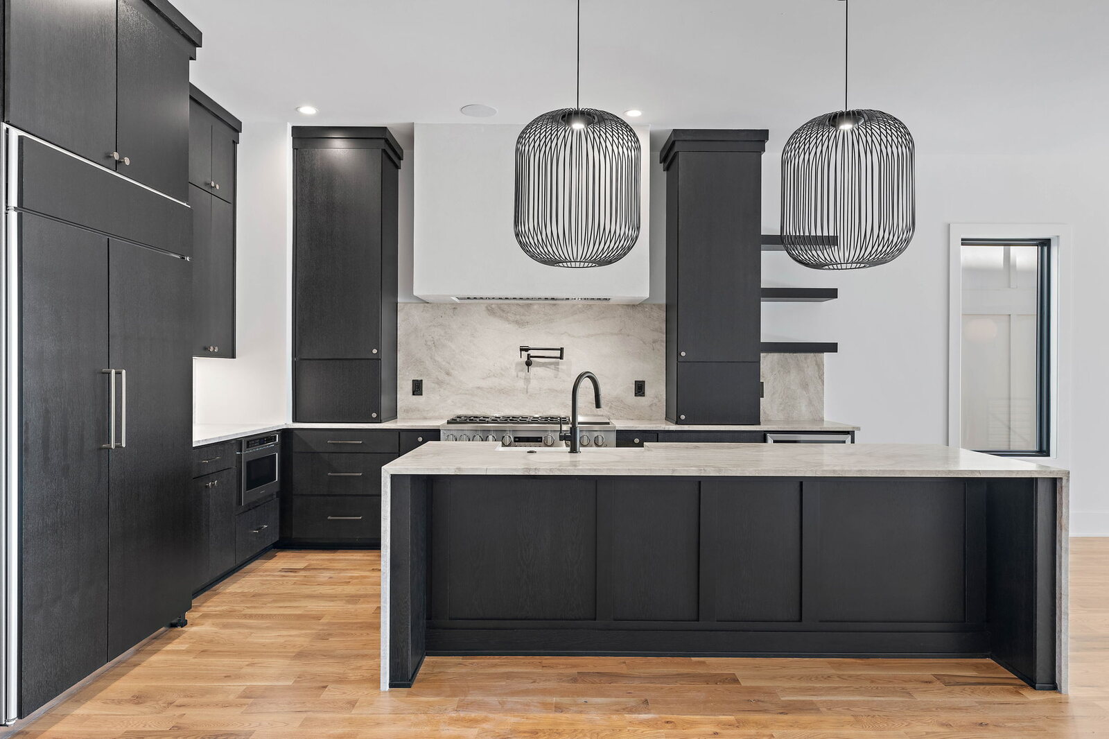 Modern contemporary kitchen with dark cabinets, waterfall island, and pendant lighting in a Mark Lynn Design home